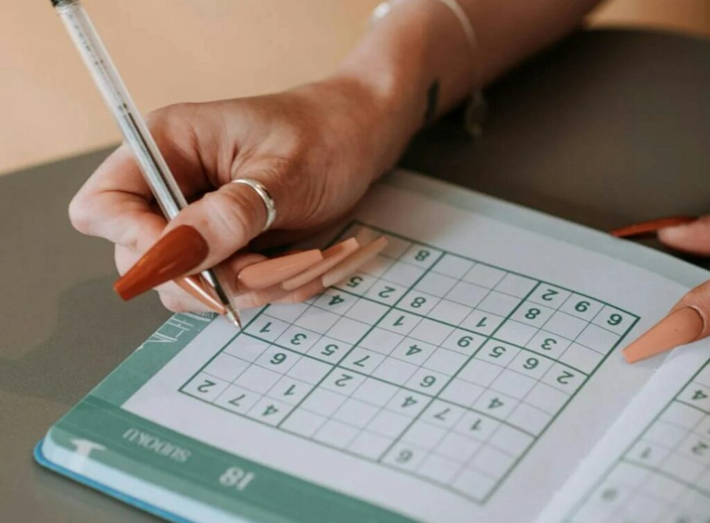Une femme écrit sur un livre de mots croisés